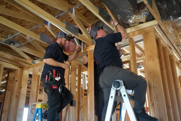 Two Five Star Mechanical techs running flex duct in a new construction home